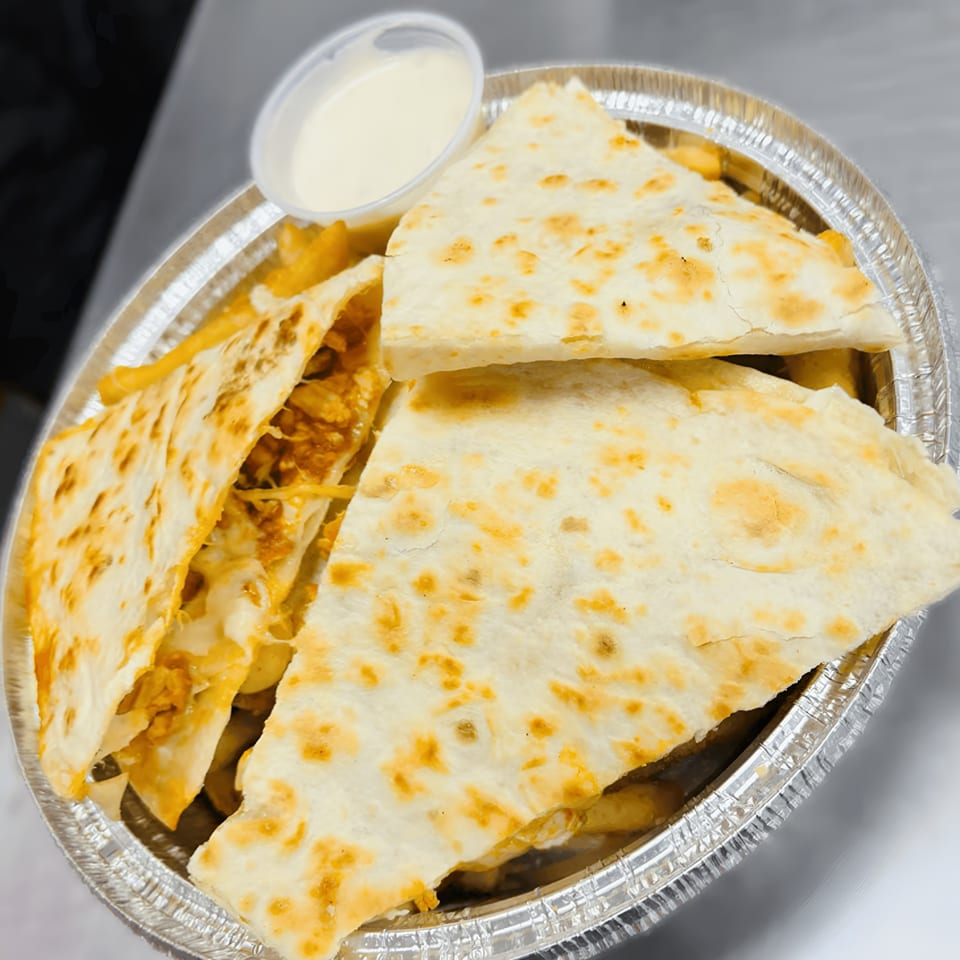 Halal chicken quesadillas with fries and a side of white sauce in a foil container.