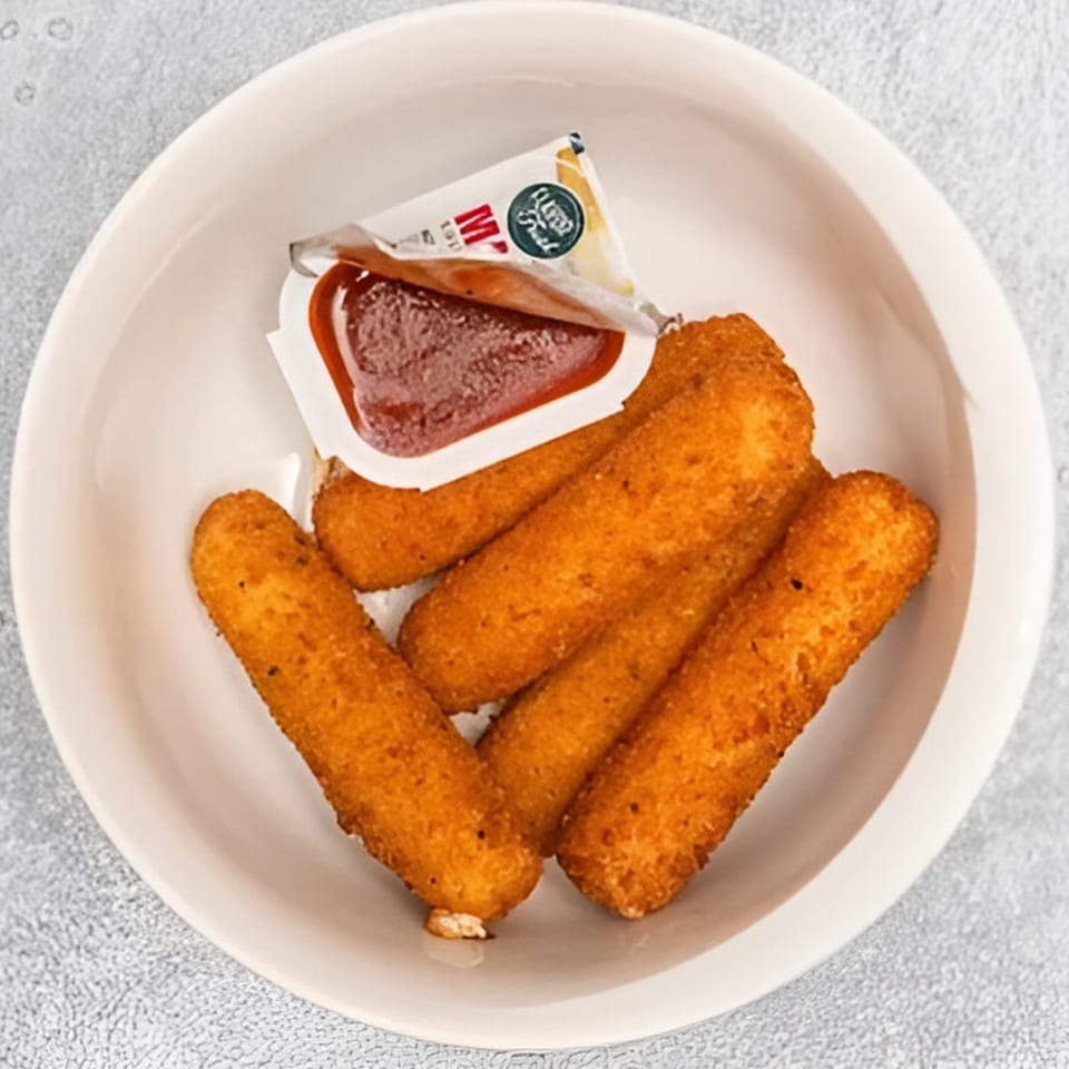 Golden-brown mozzarella sticks with a dipping sauce packet, served in a white bowl.